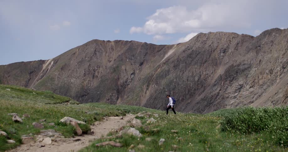 A person is hiking uphill near a mountain