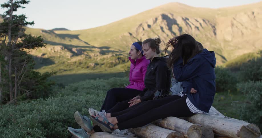 Friends sit on a stack of wood and talk