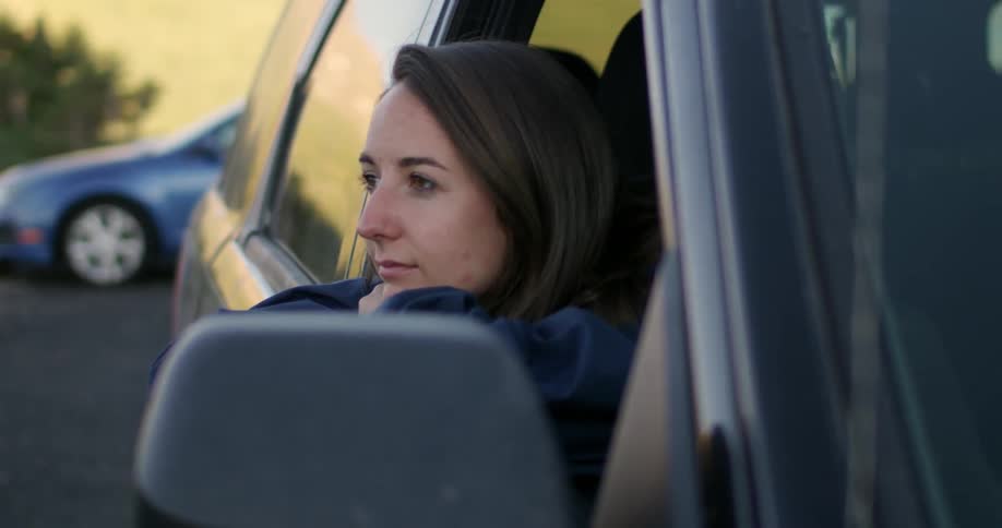 A woman is leaning out of her car smiling
