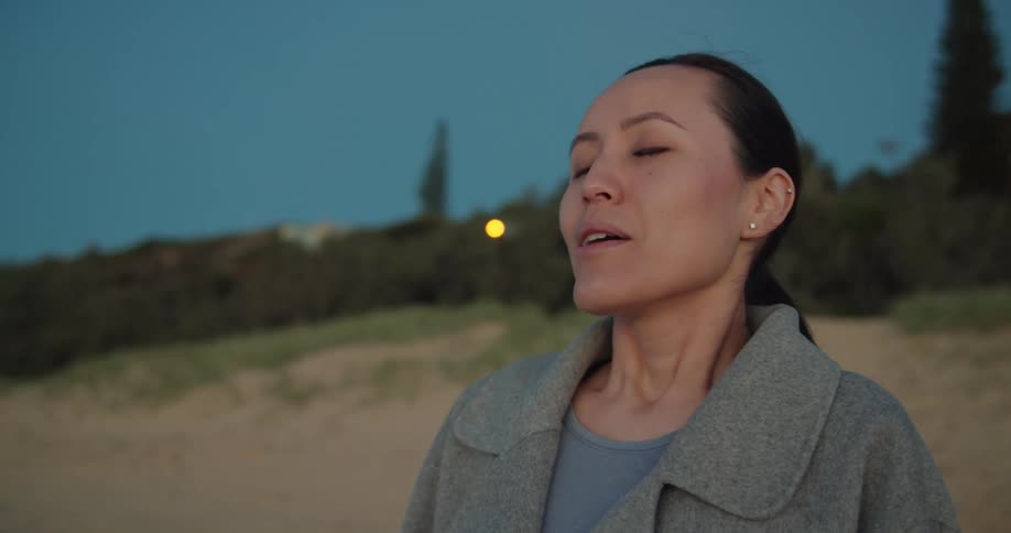 A woman takes a deep breath outside