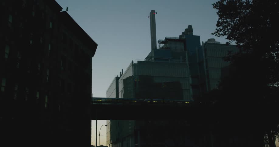 Train driving on a bridge between the buildings in a city at morning