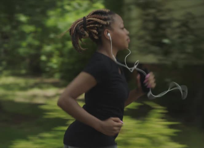A woman listening to music runs through a neighborhood for exercise