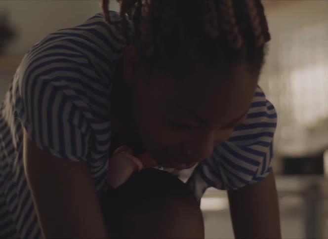 A woman in a room hovering over a little girl with a wall and window in the background