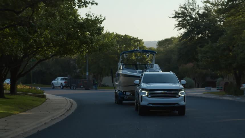 A truck hauls a boat down a neighborhood street