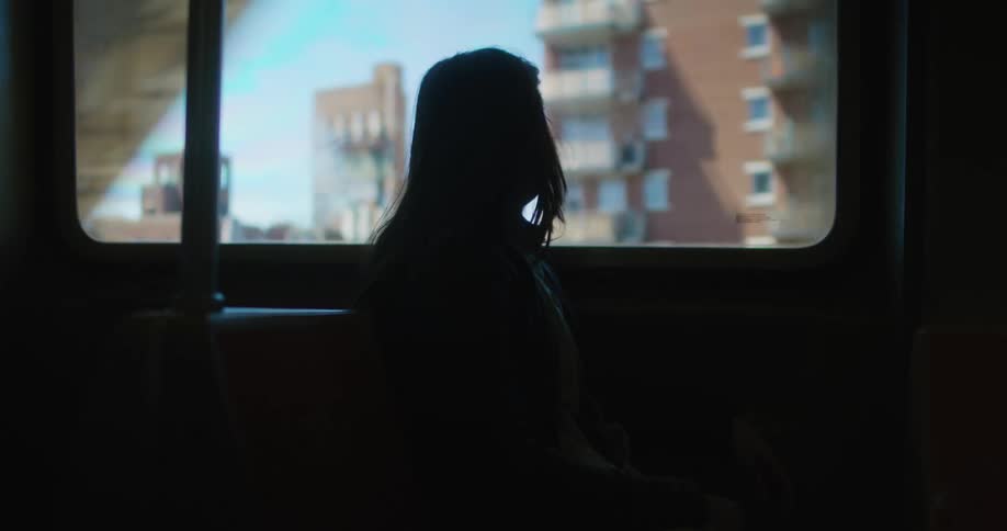 A girl sits on a bus and looks out the window