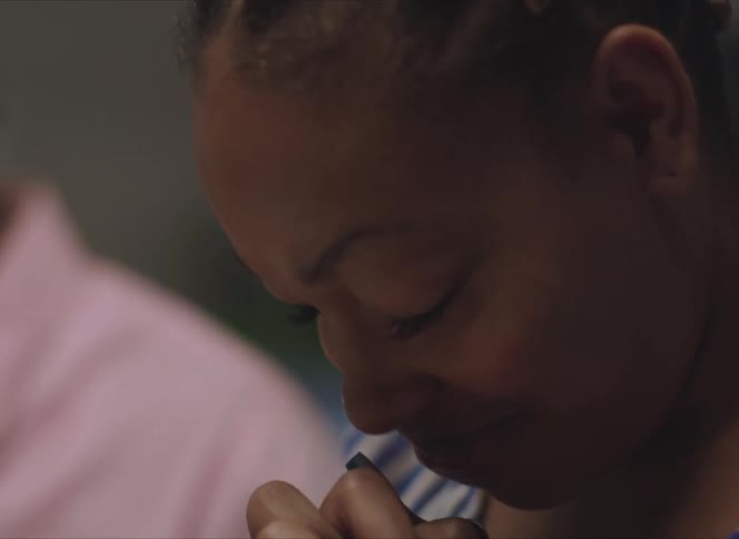 A young woman bows her head and prays