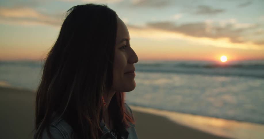 A woman is watching the sun rise on the beach