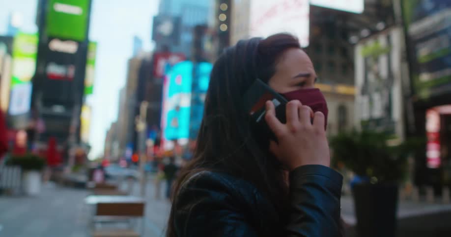 Woman with a claret red mask and a black leather jacket talks on the smartphone in downtown