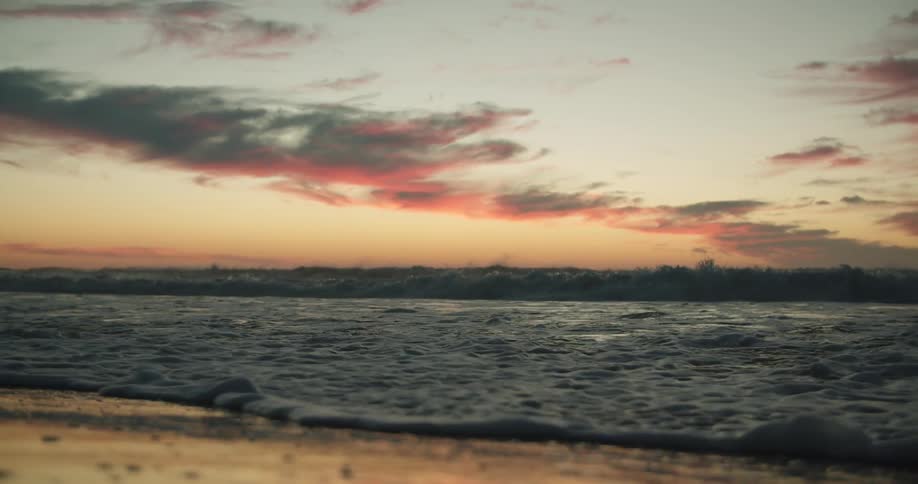Ocean water is moving fast towards the beach coast at sunset