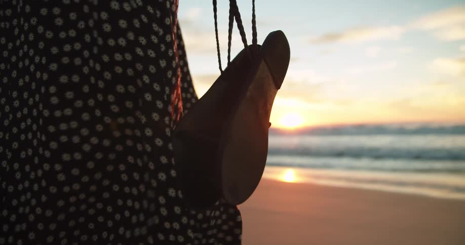 A woman standing on a beach with the ocean sky and clouds in the background