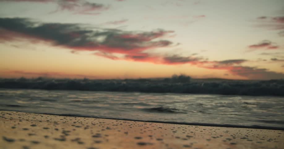 Ocean wave breaks against the coast at sunset