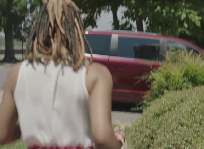 A mother rushing an elementary aged daughter to a parked van outside
