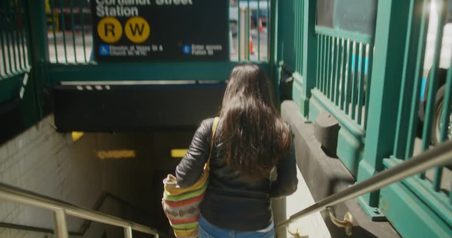 Woman goes down a stairwell to the subway in the city