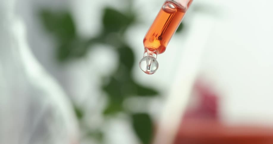 Orange liquid dripping from a glass tube