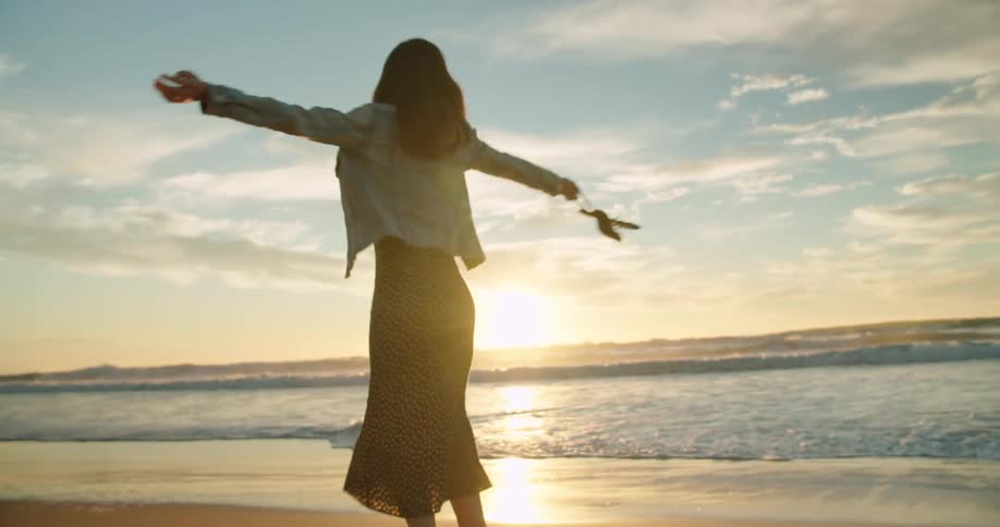 A woman spinning around on the beach