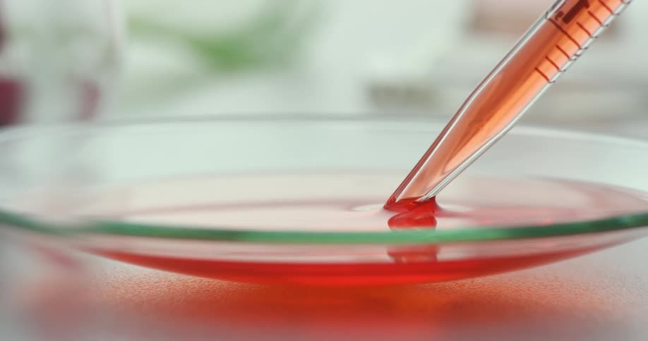 A dropper sucking up a red liquid in a plastic spoon