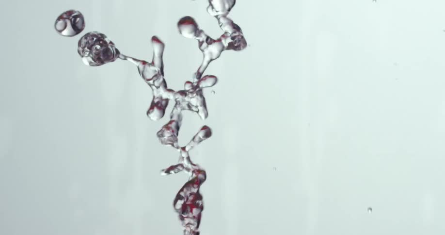 A liquid and droplets being tossed in the air and falling down with a white background