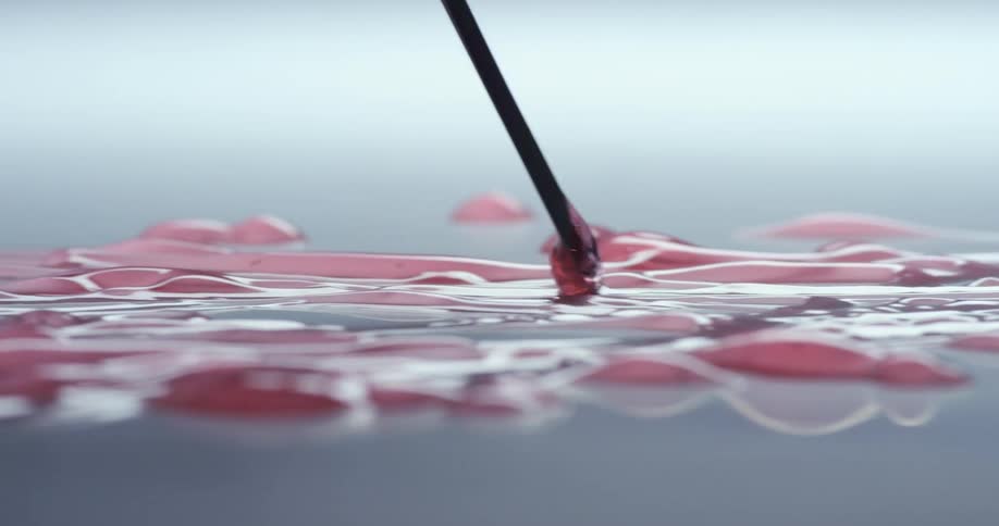 Spatula dragging clumps of pink jelly over a white surface