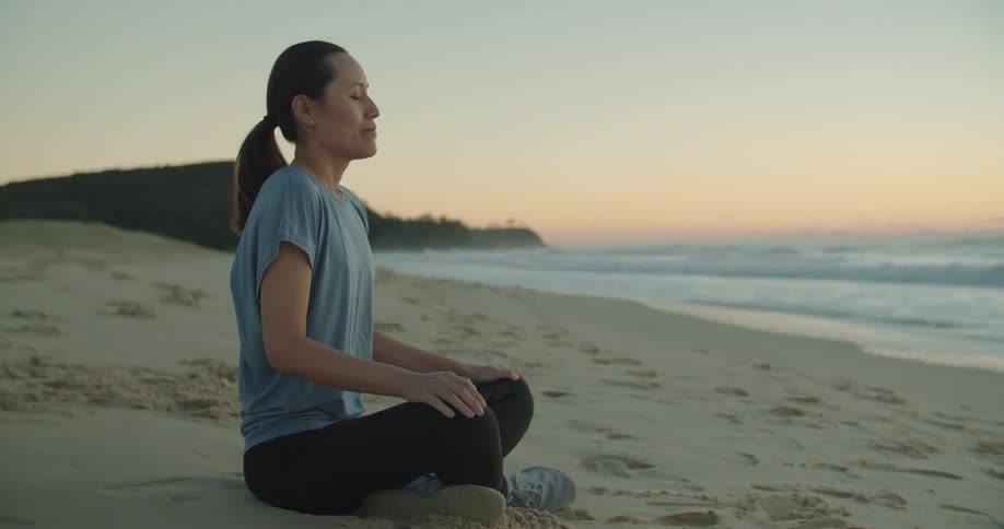 A woman meditating at the beach