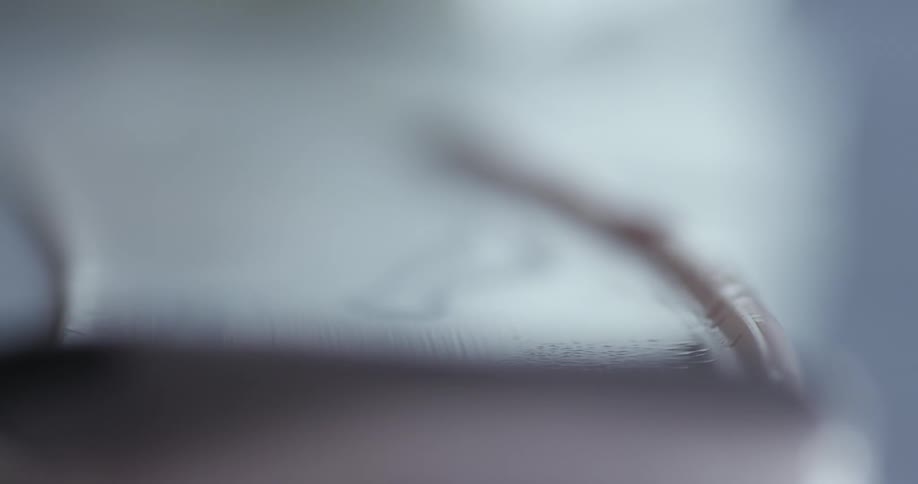Spatula spreading a thin layer of pink cream over a reflective surface