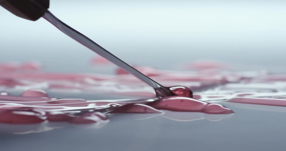 A scraper pushes pink syrup across the surface