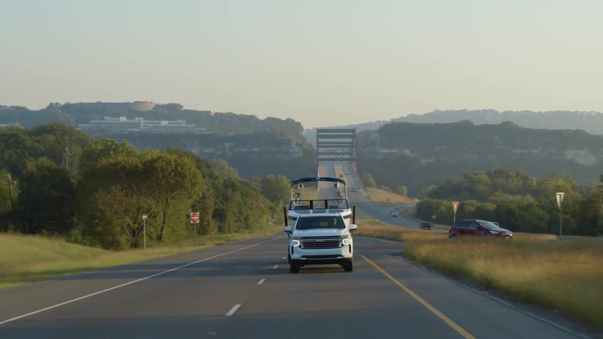 A truck is towing a boat on the highway