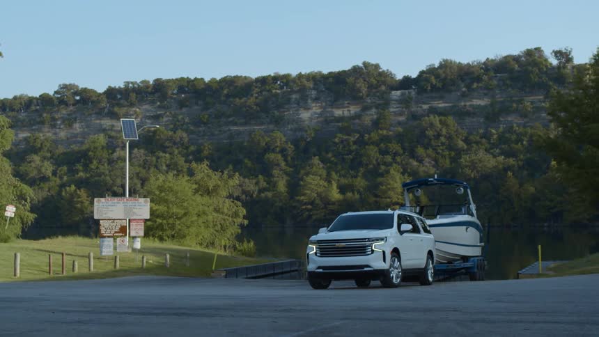 A sport utility vehicle towing a boat sits parked in a lot near a canyon