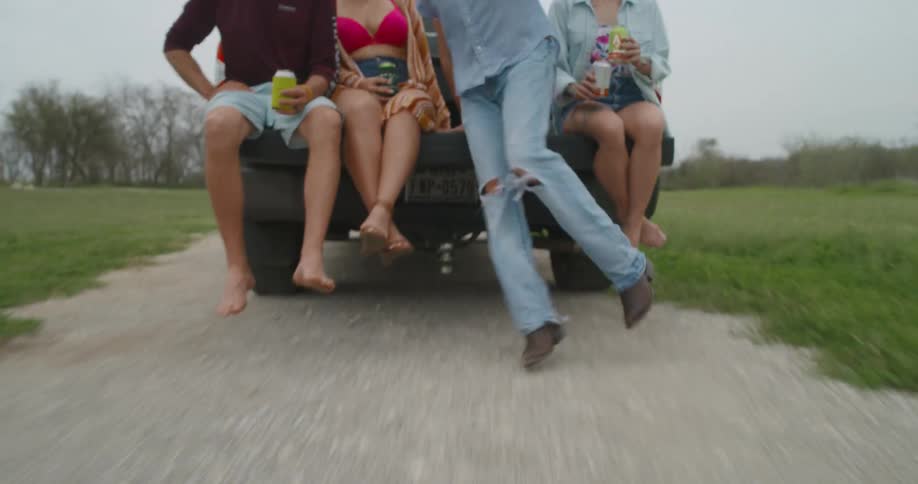 A group of people are sitting on a tailgate of a moving truck