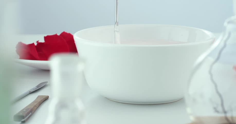 Liquid being stirred in a bowl in a room with containers and a wall in the background