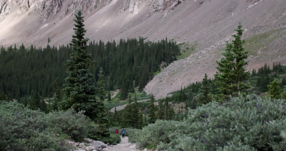 Two people are hiking near the foot of a mountain