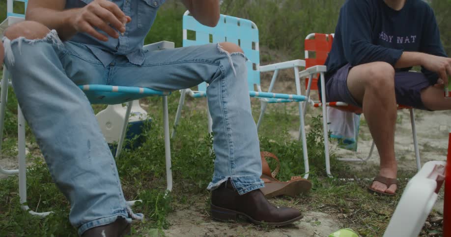Friends gathered outside in lawn chairs and drinking beers