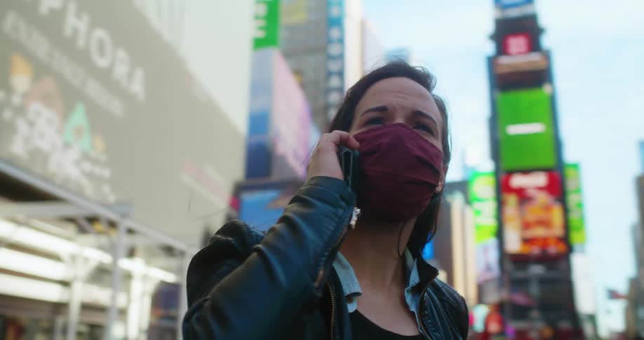A woman is walking around a downtown city and talking on a cellphone