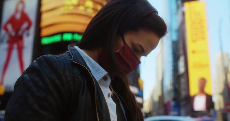 A young woman texts on her smartphone while standing in a busy tourist district