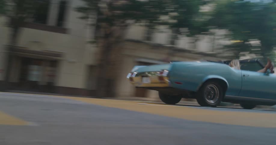 Convertible travels down the city street on a sunny day