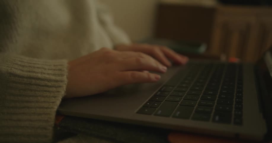 A woman scrolling on a laptop resting on herlap