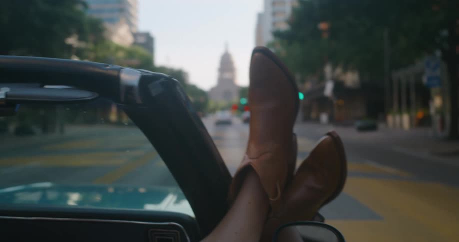 A person waves their hand while riding down the city street