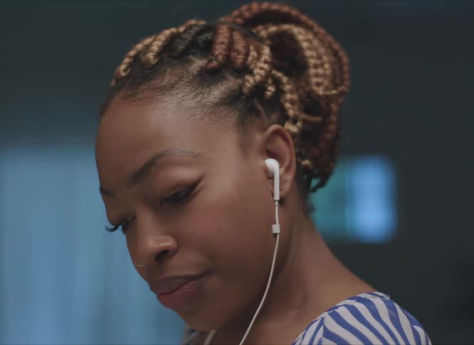 A woman putting an earbud into her left ear