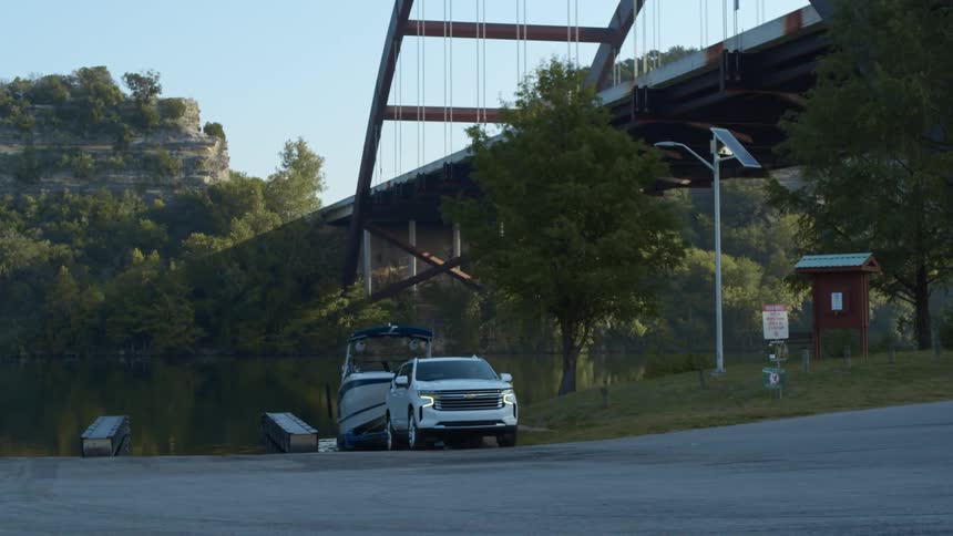 Car unloading a boat on a lake under a bridge in the morning