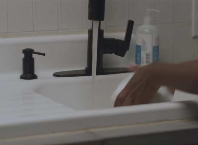 A person washes a small bowl in a small sink