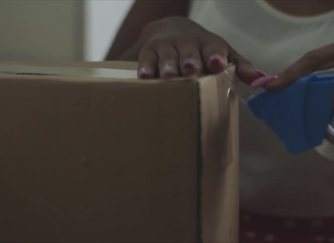 A woman is packing a cardboard box