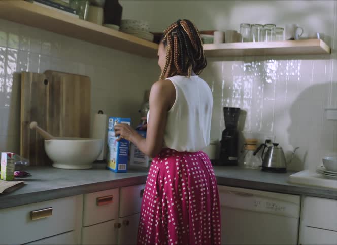 A woman moving cereal in the kitchen