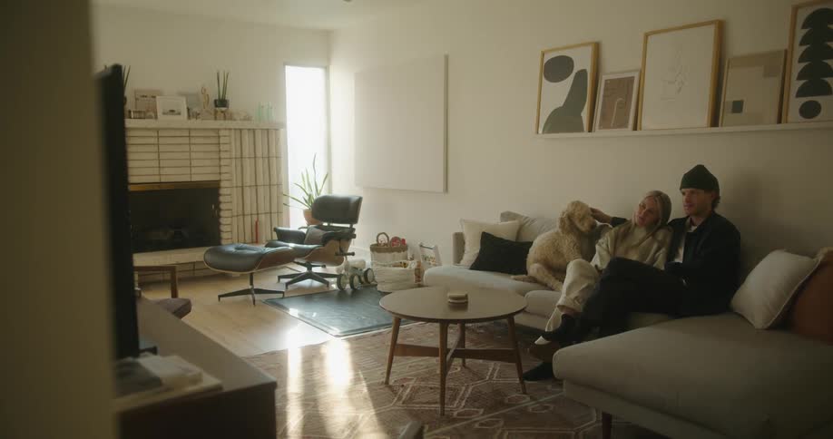 A man a woman and a dog in a room sitting on a couch