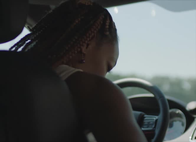 A woman buckling into the drivers seat of a car