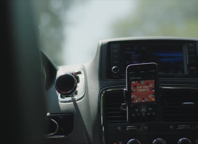 A man drives his vehicle with a cell phone mounted on the dash
