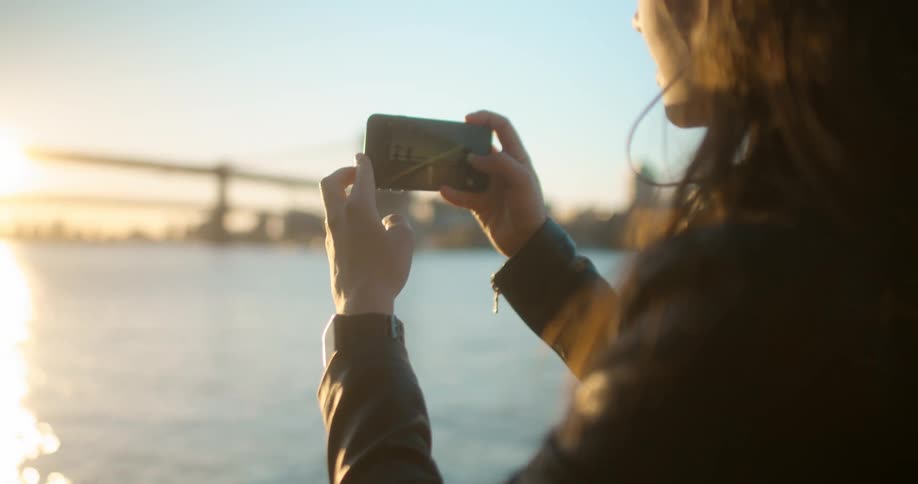 A woman raises a cell phone to take a photo