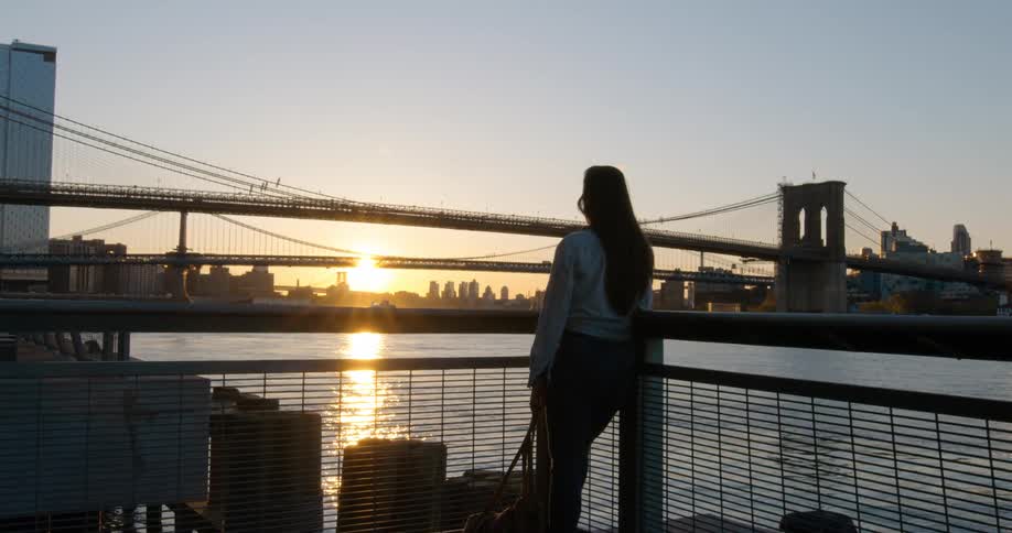 Woman standing on the terrace of a building looking at the sunset over the city