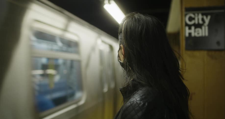A woman in a face mask waiting for a train in a subway station
