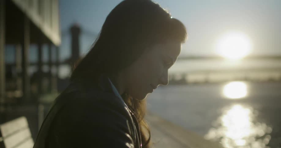A teenage girl stands on the shore and reads a book
