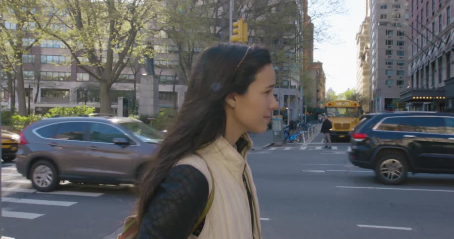 A female pedestrian walking on a busy city sidewalk in the daytime