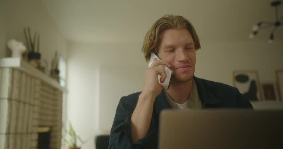 A man sitting and talking on his phone in a room
